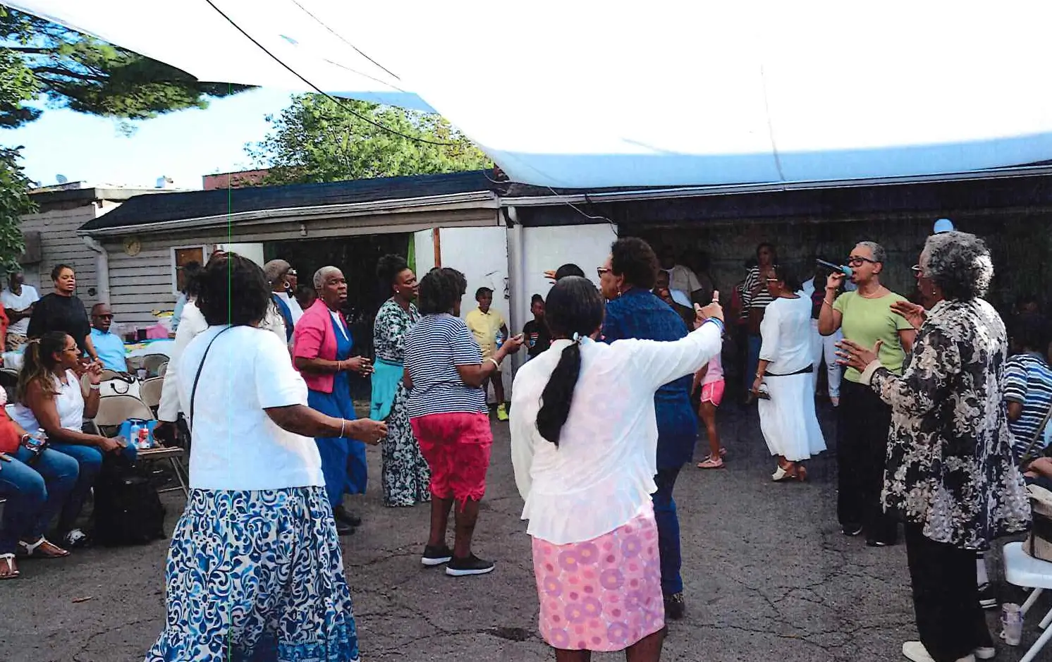 A group of people gathered outdoors, some dancing or socializing.